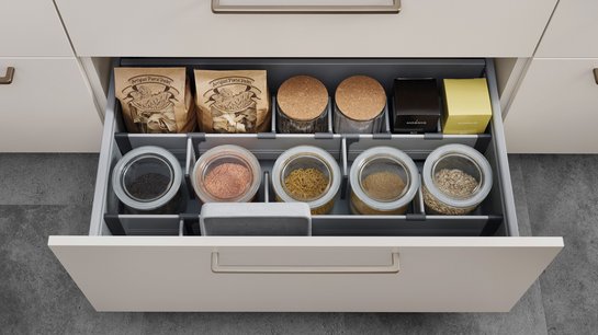 Offene Küchenschublade, darin ein mit Teilern eingeteiltes Ordnungssystem und Lebensmitteln