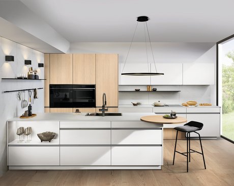 Moderne Küche mit weißen Fronten, Holzhochschränken und Kochinsel mit Theke.