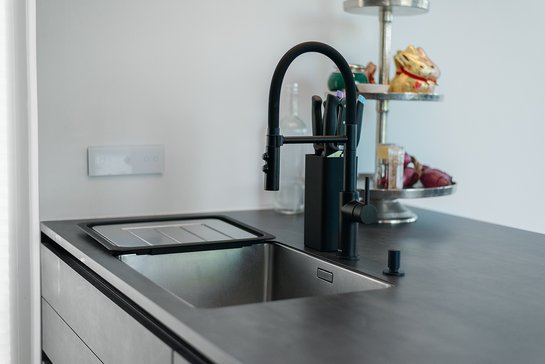 Schwarze Spüle, die im Unterbau in die Arbeitsplatte eingebaut wurde, passend dazu eine schwarze Armatur