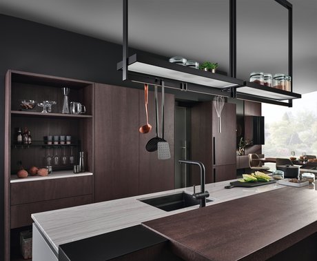 Kücheninsel mit heller Arbeitsplatte und dunkler Barplatte, dahinter eine Hochschrankgruppe in eiche dunkel