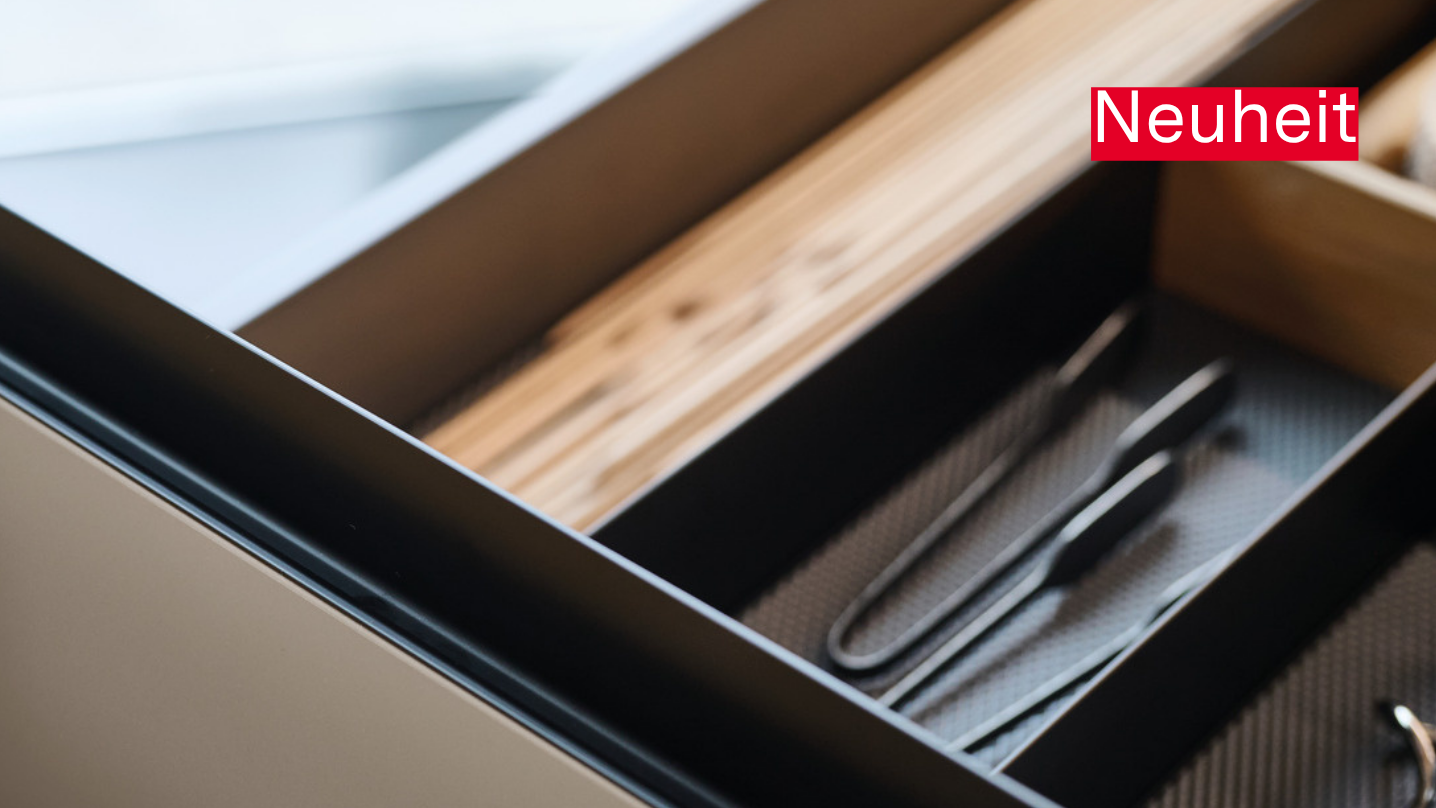 ewe GL30 in schwarz eloxiert gezeigt an ewe nanoo® . ewe Nordic in lehmbraun . eiche dunkel nordic, 18er Raster Schublade mit schwarzer Gl30 Griffleiste und Inneneinteilung.