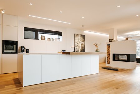 Weiße Inselküche mit Barplatte aus Holz, aufgesetzt auf der Kücheninsel