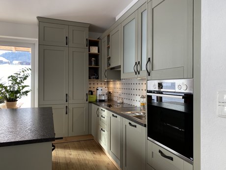 Inselküche mit Rahmenfronten im Landhausstil in salbei mit schwarzer Arbeitsplatte