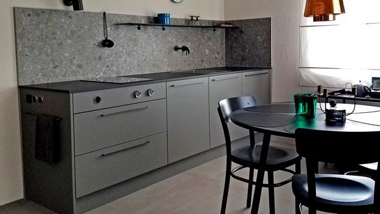 Sehr kleine kompakte Küchenzeile in grau mit grau gemusteter Rückwand ohne Oberschränke