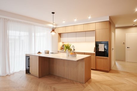 Inselküche mit Naturstein-Arbeitsplatte und Blick zur Küchenzeile mit Hochschränken.