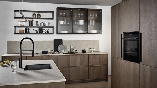 Inselküche in carameleiche mit heller Arbeitsplatte, dunkler Spüle und Wandregalen