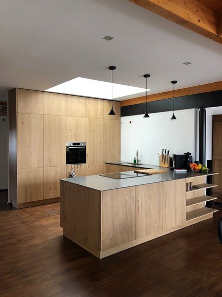 Inselküche mit hellen Holzfronten und deckenhoch verbauten Hochschränken