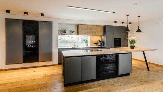 Graue INselküche mit angebautem Esstisch aus Holz