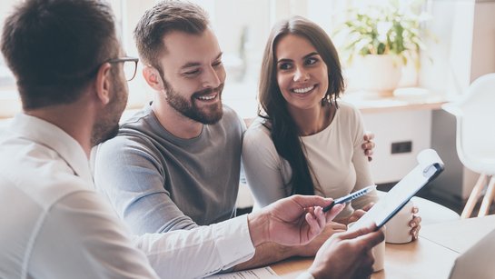Ein Paar wird von einem Berater am Schreibtisch beraten
