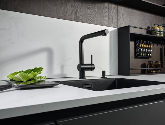 Helle Arbeitsplatte mit schwarzer Spüle und Armatur, dahinter angeschnittenes offenes Metallwandregal