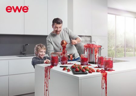 Vater und Sohn in weißer Küche beim Marmelade-Einkochen, alles tropft und spritzt