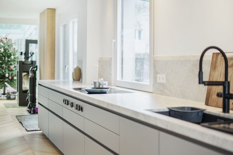 Küchenzeile in der hellen Farbe taupe, dahinter ein Fenster, mit einer schwarzen Spüle