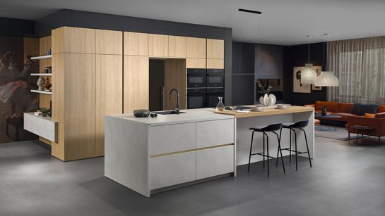 ewe Cemento . ewe Nordic in malta alabaster . bergeiche nordic, schräge Hauptansicht Moderne graue Inselküche mit integrierter Bar und Hochschränken aus hellem Holzfurnier