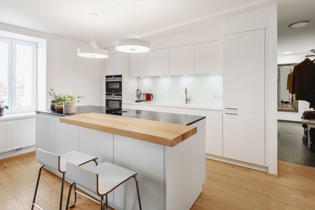 Weiße Inselküche mit Holz-Thekenplatte und Barstühlen