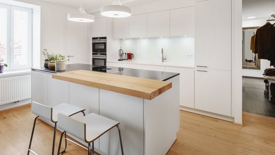 Weiße Inselküche mit Holz-Thekenplatte und Barstühlen