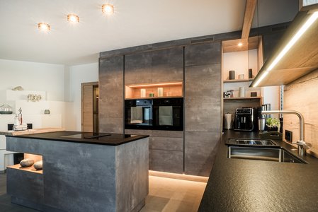 Industrial Style Inselküche mit Betonoptik-Oberfläche und schwarzer Arbeitsplatte