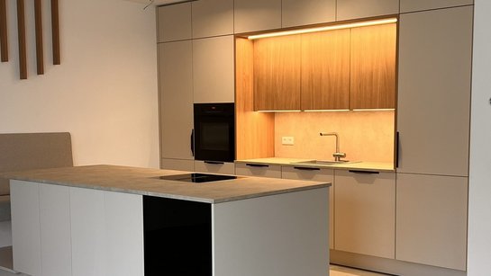 Gesamtansicht der Küche mit deckenhohen Hochschränken und harmonischer Kombination aus sand und eiche cognac.