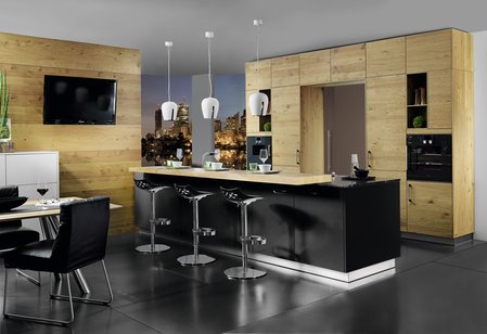 ewe Lucca in schwarz Hochglanz mit Hochschränken in wildeiche Kücheninsel in schwarz Hochglanz und Barhockern, dahinter Hochschränke in wildeiche