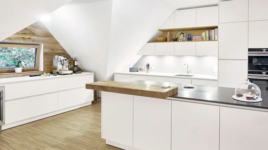 Weiße Küche mit Thekenplatte aus Holz, die perfekt an einen Raum mit Dachschräge angepasst wurde