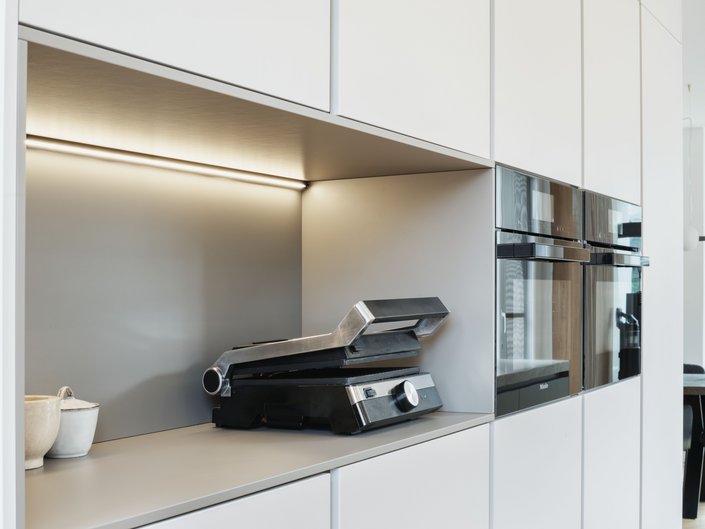 Hochschrankgruppe in der hellen Farbe angora mit einer Nische, darin ein Sandwichtoaster