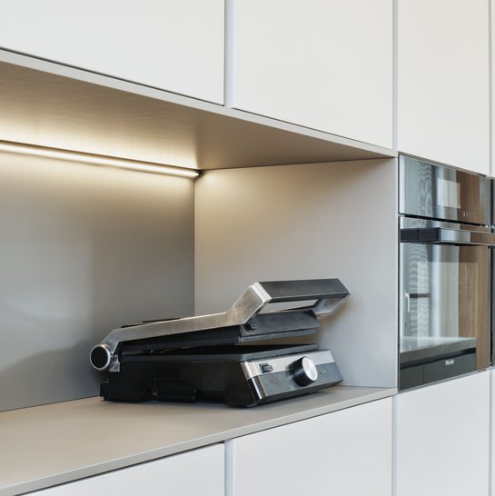 Hochschrankgruppe in der hellen Farbe angora mit einer Nische, darin ein Sandwichtoaster