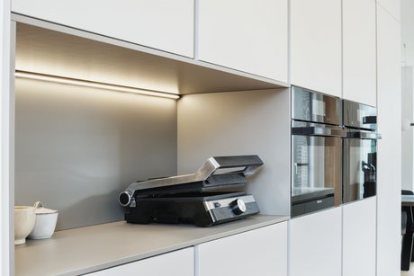 Hochschrankgruppe in der hellen Farbe angora mit einer Nische, darin ein Sandwichtoaster