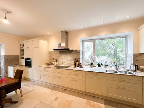 L-förmige Landhausküche mit Rahmenfronten in altweiß ohne Oberschränke