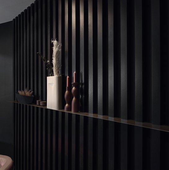 Schwarze Wandverkleidung im Paneel-Stil mit Wandbord
