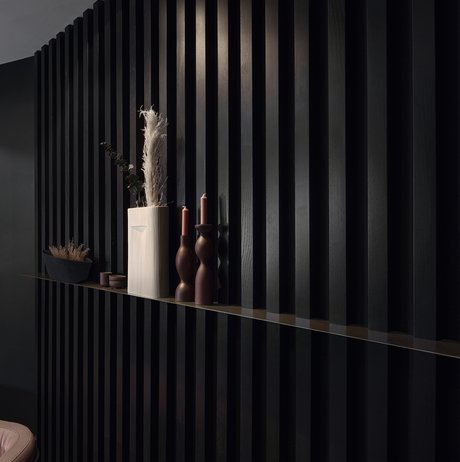 Schwarze Wandverkleidung im Paneel-Stil mit Wandbord