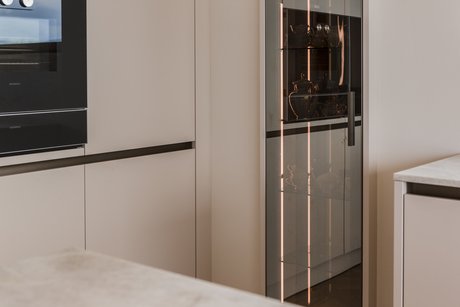 Detailansicht des beleuchteten Glasvitrinenschranks mit eleganter Innenbeleuchtung und reflektierenden Glasflächen.