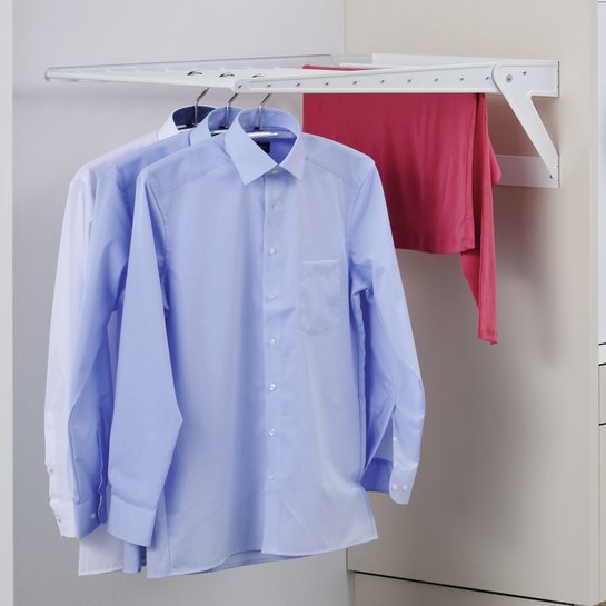 Wandmontierter Wäschetrockner, auf dem zwei Hemden und ein Shirt hängen.