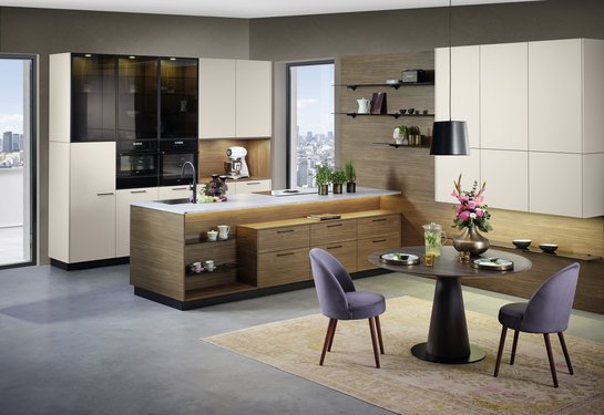 Moderne ewe Küche in der Farbe angora mit Kücheninsel in nuss pavia und Esstisch mit Stühlen