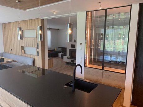 Moderne Küche mit 2 cm starker Granit-Arbeitsplatte, flächenbündig integriertem mit Induktionskochfeld sowie schwarzer Spüle und Armatur.