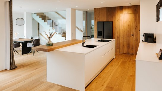Inselküche in weiß mit seitlicher Hochschrankgruppe mit Holzfronten