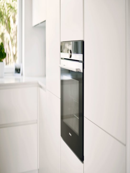 Detailfoto eines weißen Hochschranks in der Küche mit schwarzem Backofen