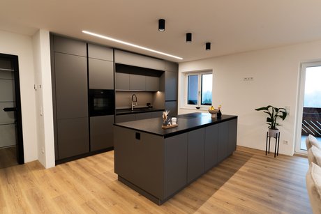 Gesamtansicht der modernen Inselküche im Modell ewe nanoo® in basaltgrau mit großzügiger Kücheninsel und deckenhoher Hochschrankplanung.