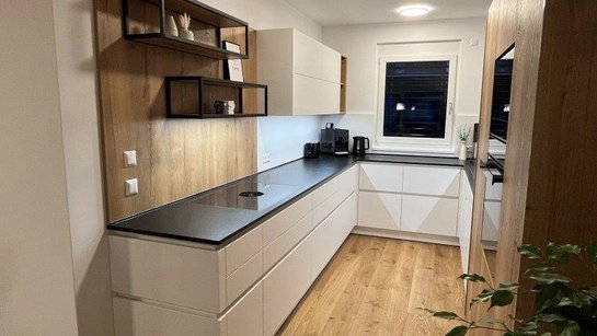 U-förmige weiße Küche mit schwarzer Arbeitsplatte aus Stein und Holzrückwand