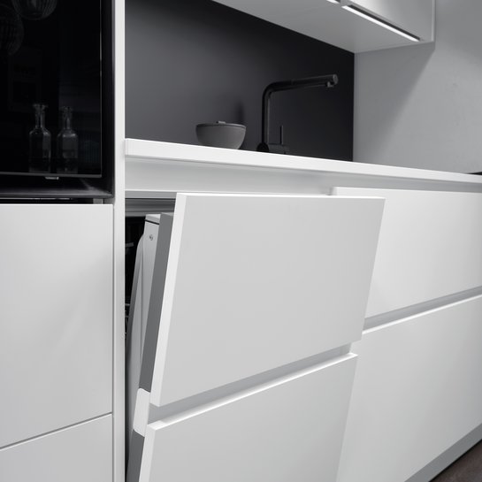Weiße grifflose Küchenzeile mit leicht geöffnetem Geschirrspüler 