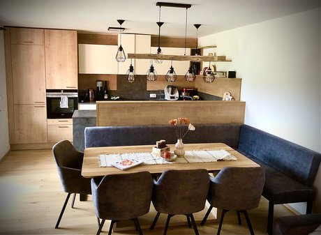 Esstisch-Sitzecke, dahinter eine Inselküche