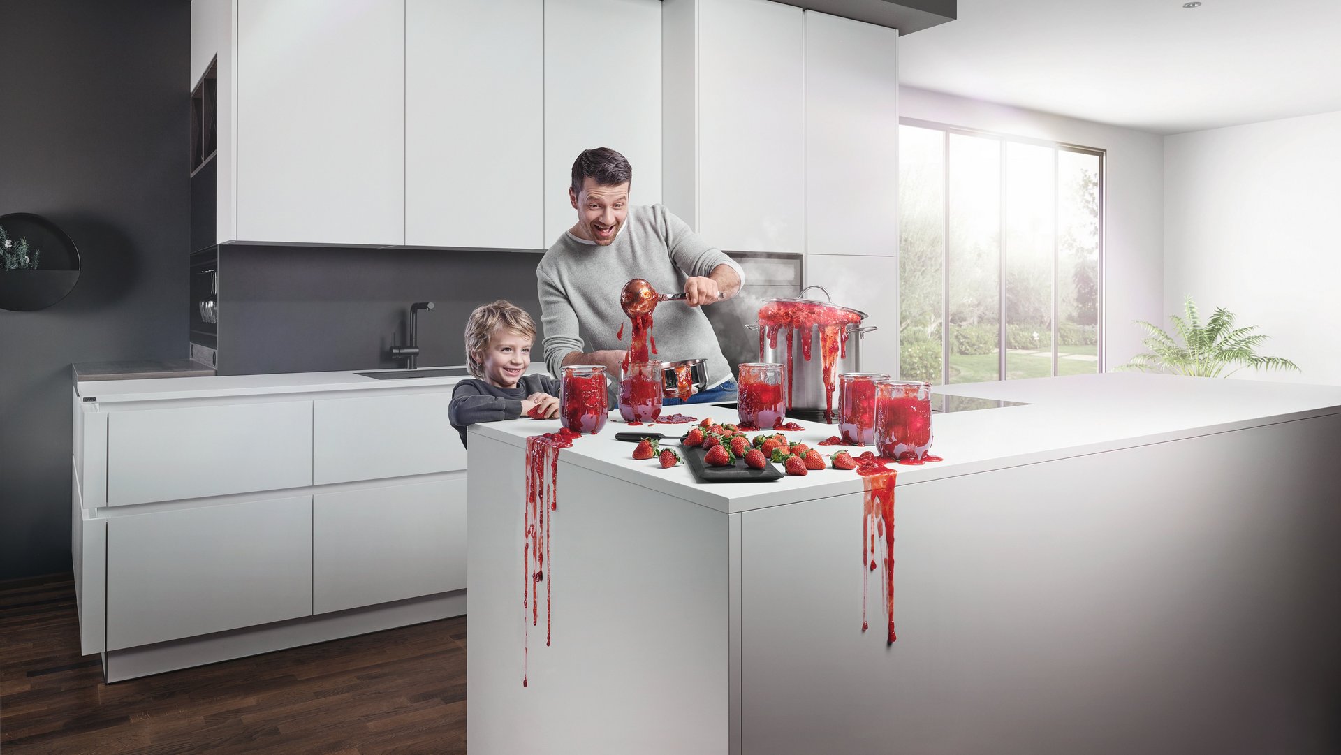 ewe nanoo® Vater und Sohn in weißer Küche beim Marmelade-Einkochen, alles tropft und spritzt