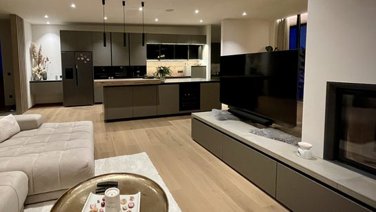 Wohnzimmer mit grauem Sideboard in der gleichen Farbe wie die Küche im Hintergrund