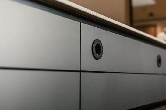 Detailaufnahme einer grauen Küchenfront mit schwarzen Steckdosen