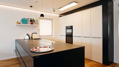 Inselküche mit dunkler Kücheninsel und weißer Hochschrankgruppe