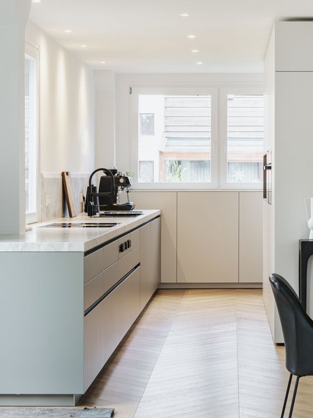 Helle Küche mit Küchenzeile links und Hochschrankgruppe rechts, davor eine dunkle Essgruppe