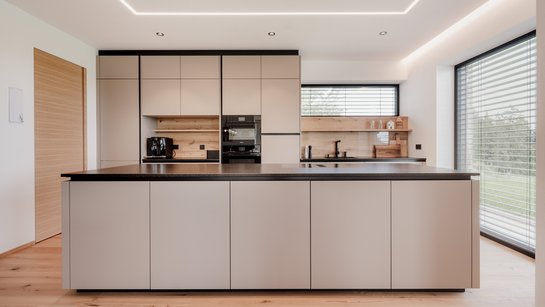 Inselküche im braun-beige-Farbton fango mit schwarzer Steinarbeitsplatte