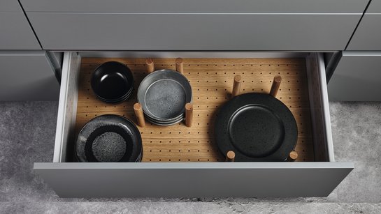 Offene Küchenschublade mit Innenausstattung aus Eiche mit Tellerhaltern