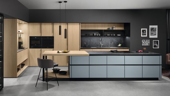 Graue Kücheninsel vor Hochschränken aus heller Eiche