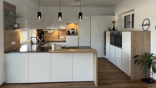 U-förmige weiße Hochglanzküche mit Holzelementen