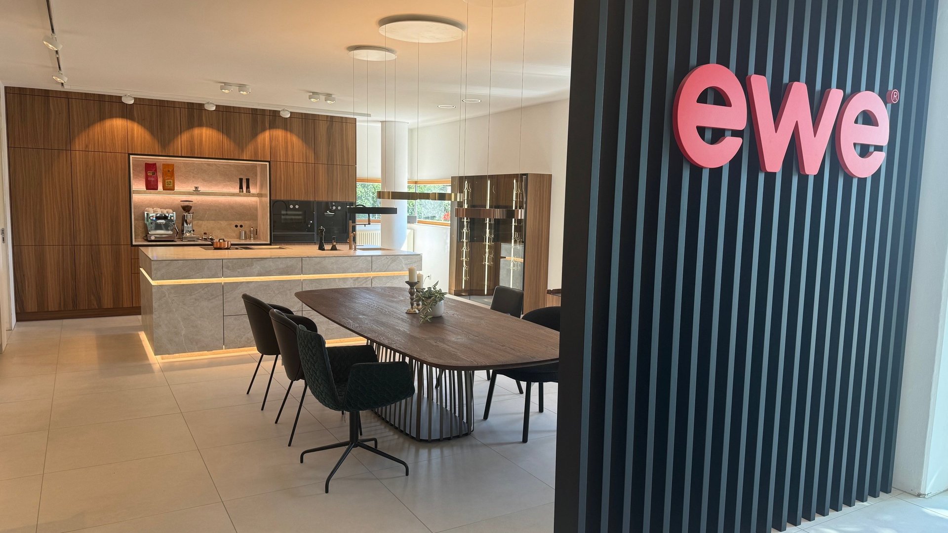Liegl Küchen | ewe Exklusiv Partner Küchenschauraum mit großem ewe Logo auf Paneelen und einer Ausstellungsküche