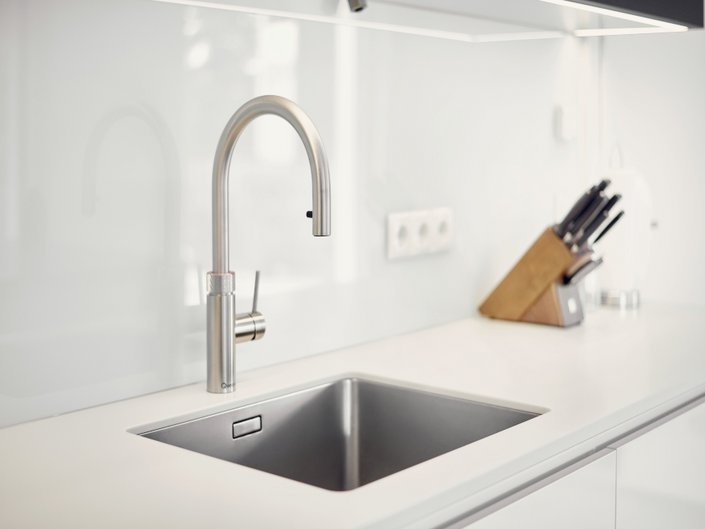 Graue Silgranit-Spüle mit silberner Armatur auf einer weißen Küchenzeile